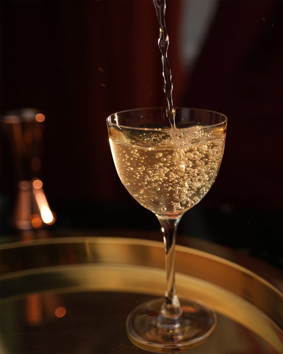 Sparkling wine being poured into a coupe