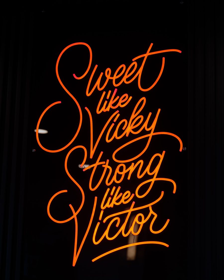 A neon sign in script reading Sweet like Vicky, Strong like Victor