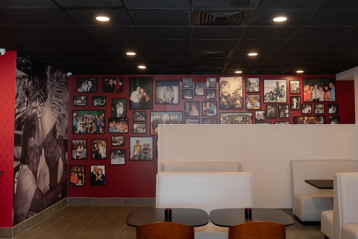 A red wall covered in framed photographs inside Bar Victor