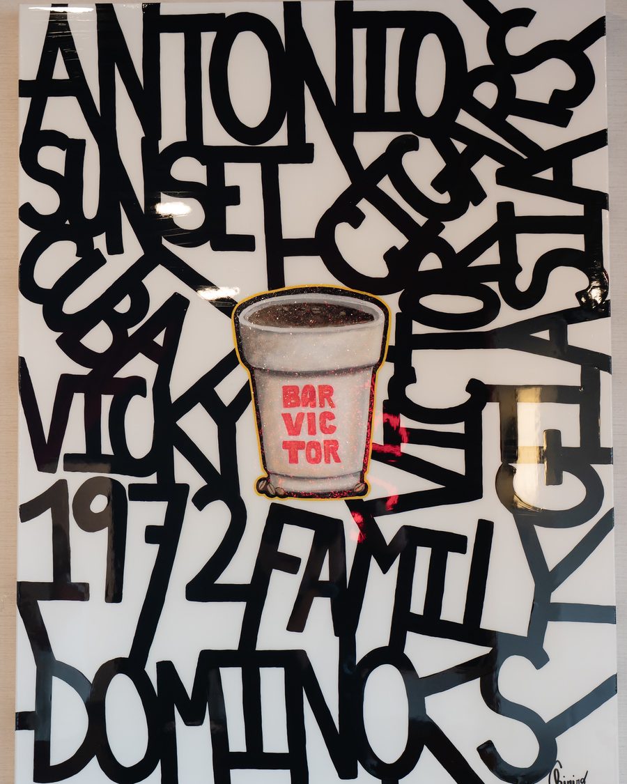 A hand-painted black-and-white wall of words, with a Bar Victor cup at its center